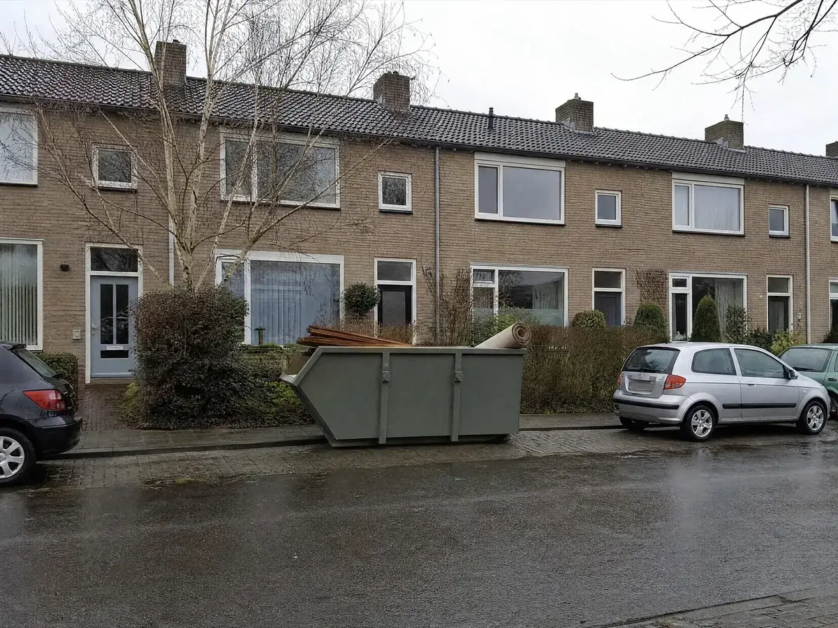 Nederlandse woonstraat met rijtjeswoningen en een afvalcontainer voor de deur